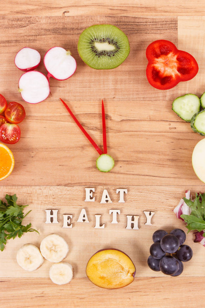 Reloj hecho de frutas y verduras que contienen vitaminas que muestran el tiempo de 23 horas 55 minutos, concepto de resoluciones de año nuevo de la nutrición saludable - Foto, imagen