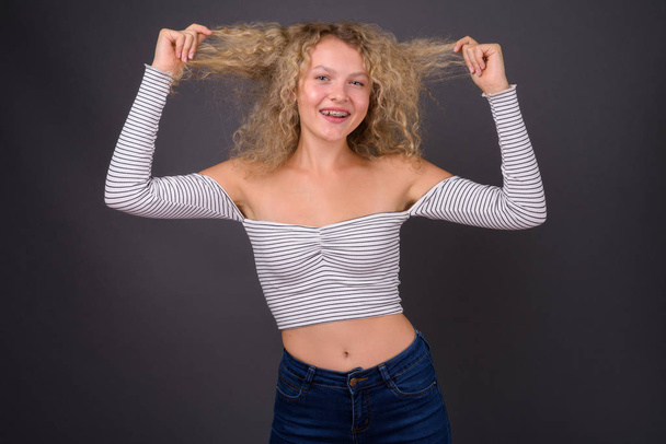 Young beautiful woman with blond curly hair against gray backgro - Foto, immagini