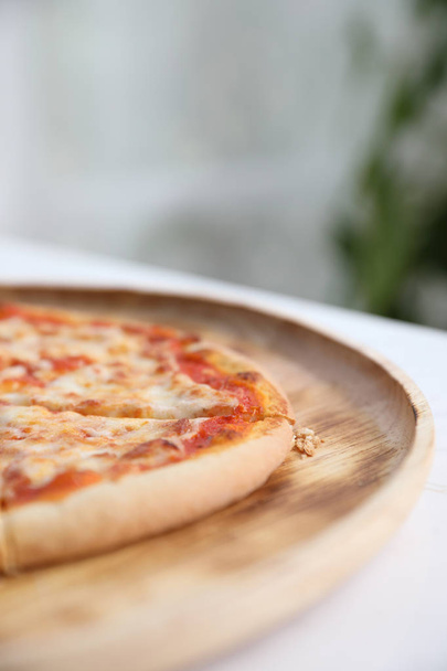 pizza margarita en plato de madera en el fondo de la cafetería
 - Foto, Imagen