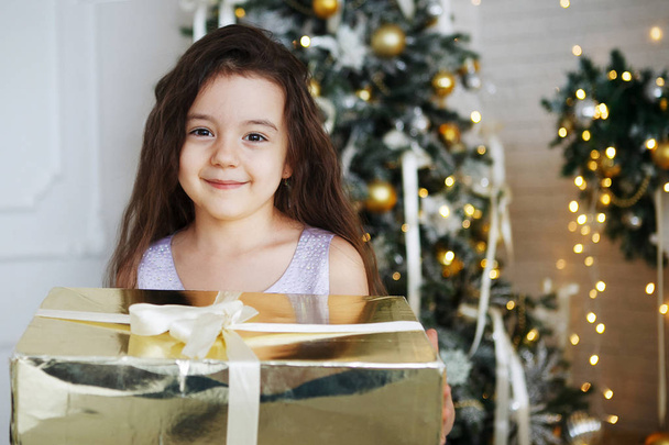Mädchen mit Weihnachtsmützen sitzt mit Geschenkschachteln in der Hand und freut sich über eine Überraschung. - Foto, Bild