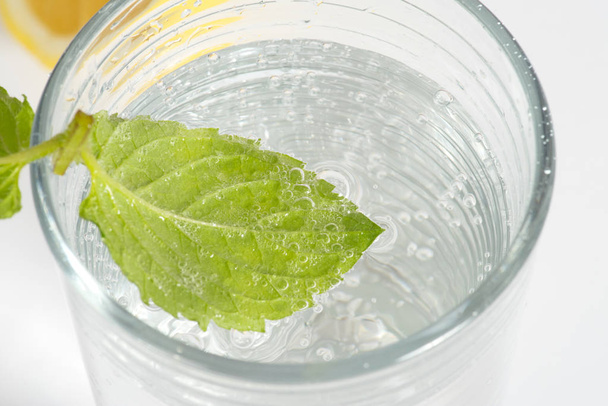 ein Blatt Minze in einem Glas Mineralwasser - Foto, Bild