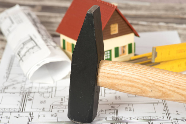 Un martillo, regla de plegado y plan de construcción para una casa
 - Foto, imagen