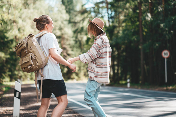 Couple travelers woman and man stand on road and  looking forward to a joint journey. Lifestyle concept. Young happy family traveling adventure vacations - Photo, Image