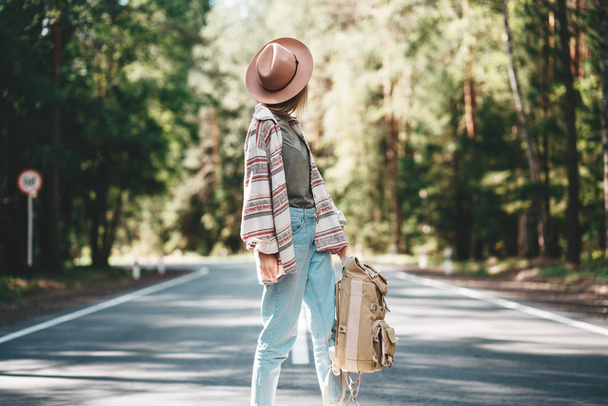 Young handsome hipster woman wearing hat and traveling backpack and stand on road - Foto, Bild