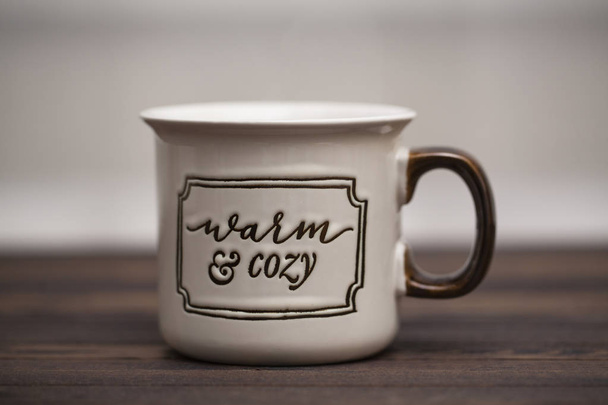 Какао с зефиром на деревянном фоне в чашке с надписью "Теплый и уютный
" - Фото, изображение