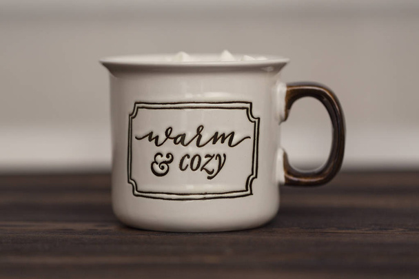 Cocoa with marshmallows on a wooden background in a Cup with the inscription " Warm and cozy" - Фото, изображение