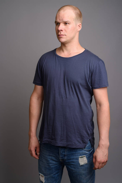 Bald man wearing blue shirt against gray background - 写真・画像