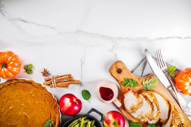 Thanksgiving holiday table with traditional festive food - turkey, pumpkin pie, pumpkins, green beans, cranberry sauce, corn, autumn apples, white marble table, top view copy space for text - Photo, Image
