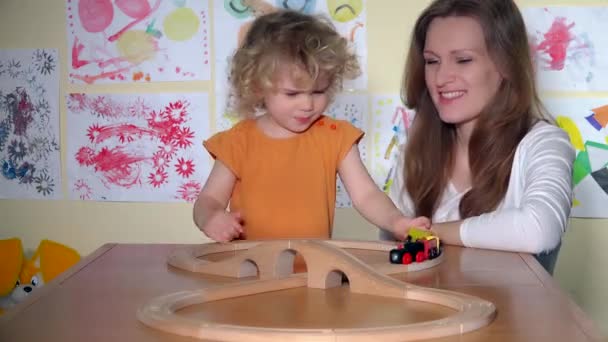 Cute little girl with pretty mother pushing toy train locomotive on railway - Footage, Video