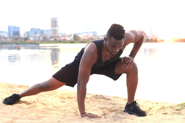 Africký muž v sportovní oblečení, rozcvičení, pláž venkovní portrét, při západu slunce nebo sunrise. - Fotografie, Obrázek
