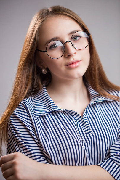 Zbliżenie portret student młoda dziewczyna w okularach na szarym tle. Kobieta uśmiechając się i patrząc na kamery - Zdjęcie, obraz