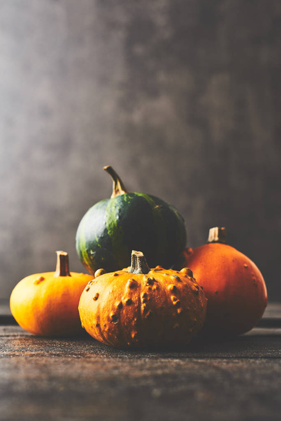 A bunch of pumpkins on black wooden rustic table over dark concrete background with copy space. Vintage retro style. Selective focus. - Foto, afbeelding