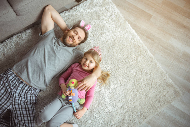 Щасливий батько обіймає дитину на підлозі
  - Фото, зображення