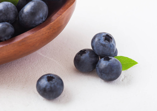Fresh raw organic blueberries with leaf in wooden bowl on white background.  - Valokuva, kuva