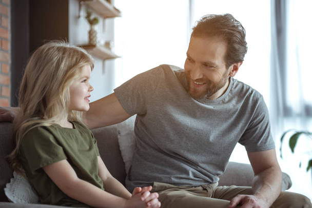 Cheerful dad talking with his child in apartment  - Foto, afbeelding