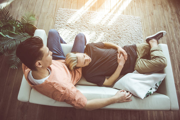 Young gay couple resting on couch at home - Фото, зображення