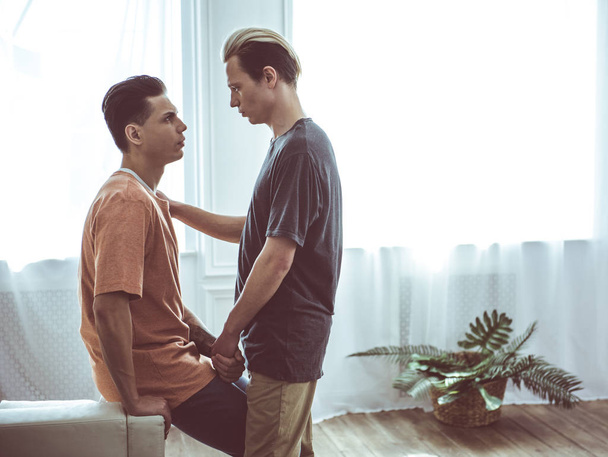 Joven pareja gay mirando el uno al otro mientras toma de la mano
 - Foto, imagen