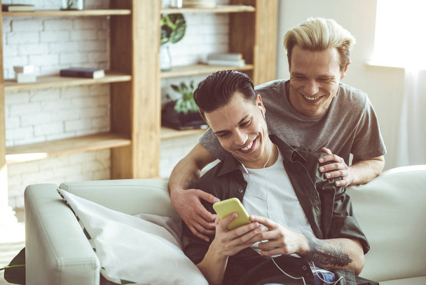 Young gay couple watching videos on smartphone at home - Foto, immagini