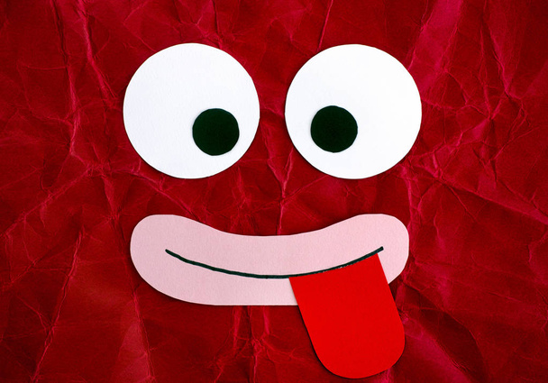 Funny face with tongue stuck out. Emotional face made from paper. Red background. - Fotó, kép