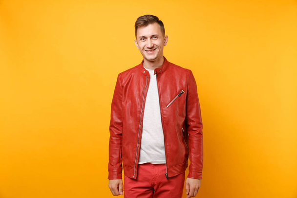 赤い革のジャケット、t シャツに孤立した明るい黄色トレンド バック グラウンドに立っての 25-30 年のハンサムな若い男を笑顔肖像画の流行。人々 の心から感情ライフ スタイルのコンセプト。広告エリア - 写真・画像