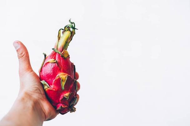 A human hand holds a fruit dragon on a white background. - Foto, Imagen