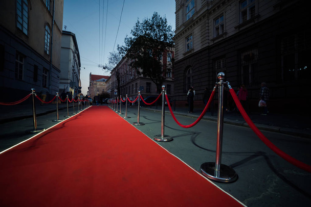 Długi czerwony dywan między liny bariery na wejście. - Zdjęcie, obraz