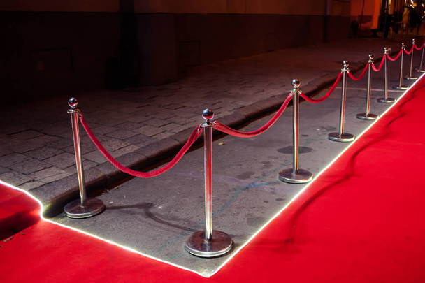 Hosszú vörös szőnyegen kötél akadályok a bejárat között. - Fotó, kép