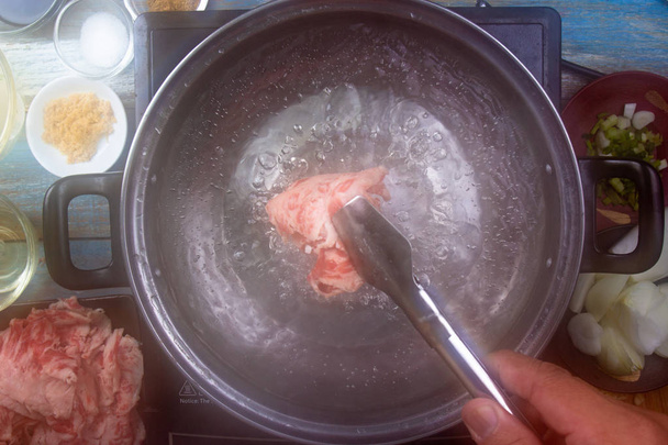 Шеф-повар обжаривает говядину с горячей водой для приготовления блюд / Концепция приготовления японской еды
 - Фото, изображение