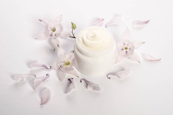 Cute flowers and petals and a jar of natural body cream isolated on white background - Zdjęcie, obraz