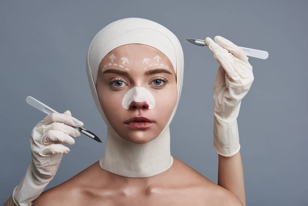 Serious woman with bandages on the head being surrounded by scalpels - Foto, immagini