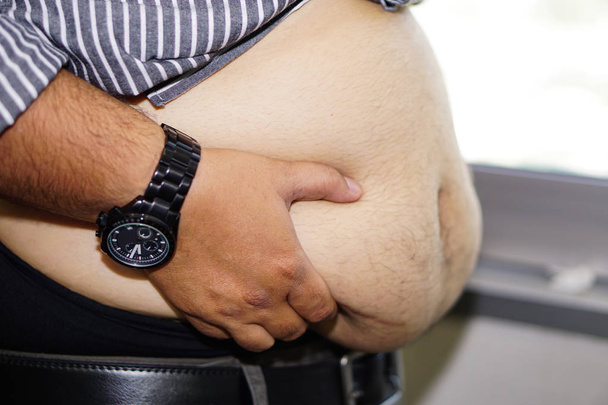 Sobrepeso mujer asiática mostrar grasa vientre en oficina. - Foto, Imagen