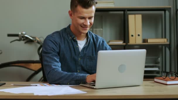 Young business man in casual shirt working in the laptop in the stylish office, finishing work day and feeling so happy. - Кадри, відео