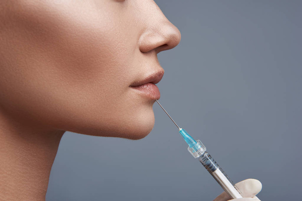 Close up of the syringe with lip injection for young lady - Фото, изображение