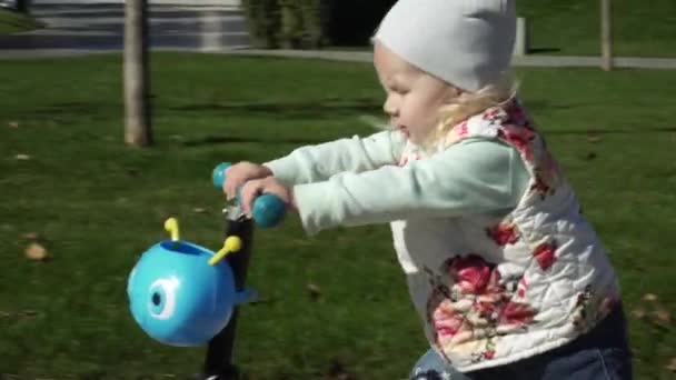 Enfant joyeux chevauchant un scooter dans le parc
. - Séquence, vidéo