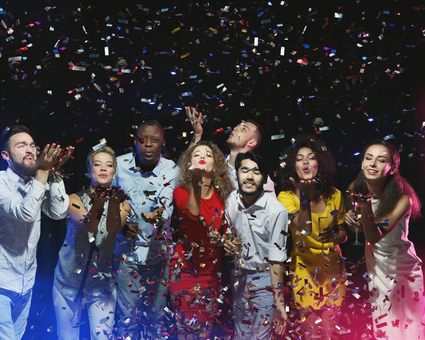 Groep vrienden genieten van partij en blazen confetti - Foto, afbeelding