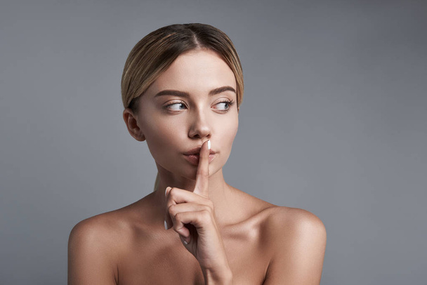 Cautious woman pressing finger to her lips and keeping quiet - Foto, Imagem