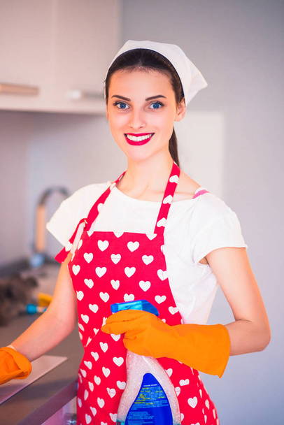 Portrait of a young smiling housewife who cleans the kitchen at home - Fotografie, Obrázek