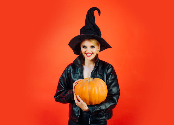 Happy Halloween. Happy gothic young woman in witch halloween costume. Witch posing with Pumpkin. - Fotó, kép