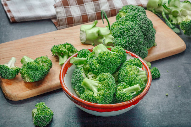 frischer roher Brokkoli in einer hölzernen Schüssel auf dunklem Hintergrund - Foto, Bild