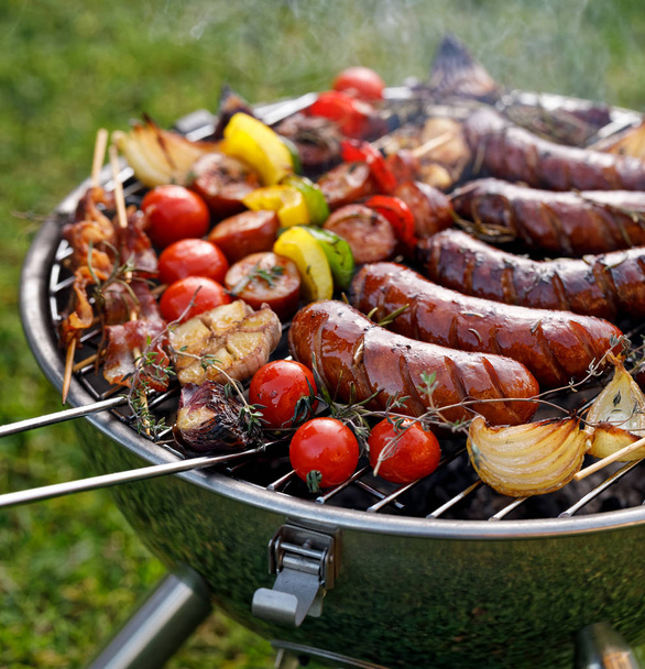 Grilovaná jídla. Různé grilované produkty: grilované klobásy, maso a zeleninové špízy, slaniny a zeleniny na grilovací deska, venku. Grilování, bbq - Fotografie, Obrázek
