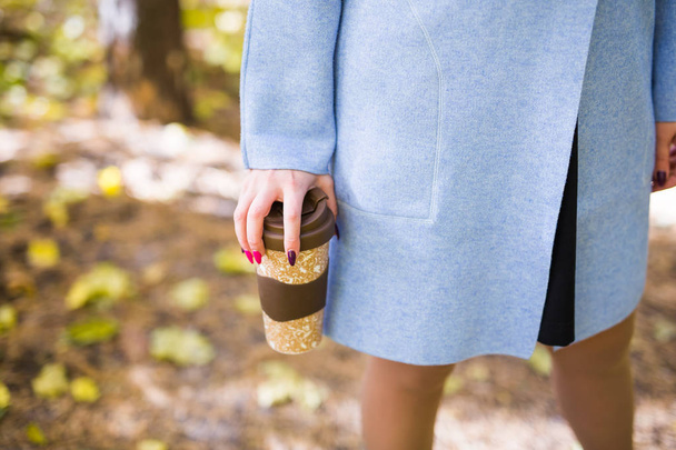 Primer plano de la mujer sosteniendo una taza de taza de café para llevar en la calle otoño
 - Foto, Imagen