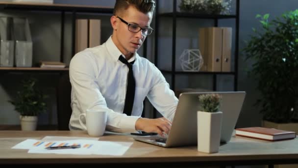 Attractive business man in casual shirt checking the finance report and using smart phone in the office at the evening. - Filmagem, Vídeo
