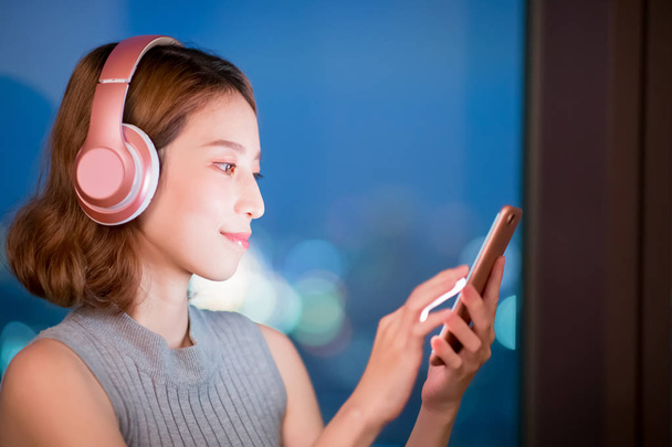 woman use phone listen music at home in the evening - Photo, image