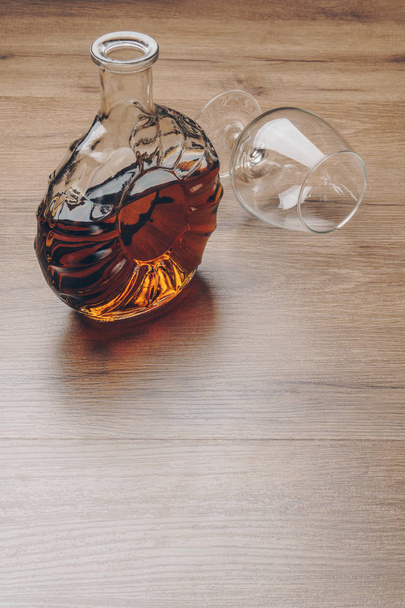 un decantador de brandy con un vaso de snifter vacío sobre la mesa de madera
 - Foto, imagen