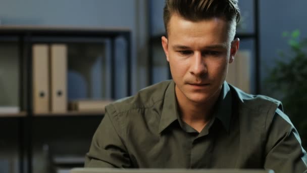 Close up shot of young business man in khaki shirt working on the laptop in the stylish office at the evening time. - Záběry, video
