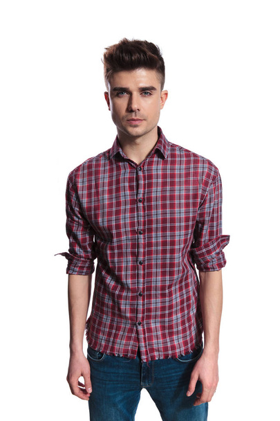 portrait of attractive young man wearing a red plaid shirt while standing on white background - Photo, Image
