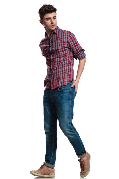 side view of attractive casual man stepping to side while holding hands in pockets, full body picture - Fotoğraf, Görsel