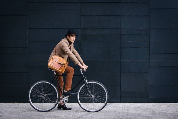 Young handsome man with casual clothes driving bycicle - Young student portrait, concepts about business, mobility and lifestyle - Фото, изображение