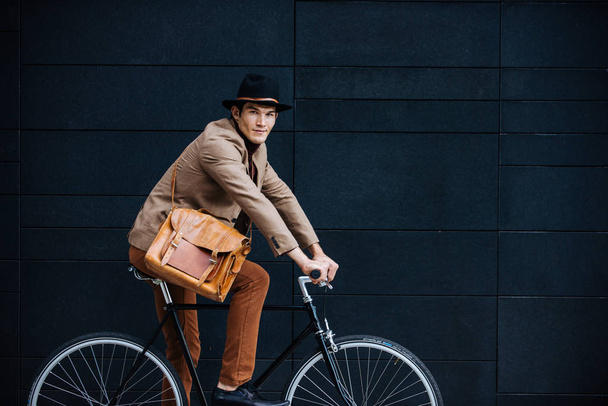 Young handsome man with casual clothes driving bycicle - Young student portrait, concepts about business, mobility and lifestyle - 写真・画像