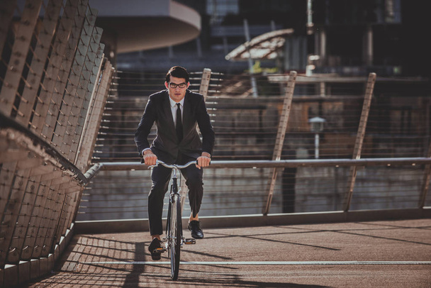 Young handsome man with business suit driving bycicle - Corporate businessman portrait, concepts about business, mobility and lifestyle - Photo, image